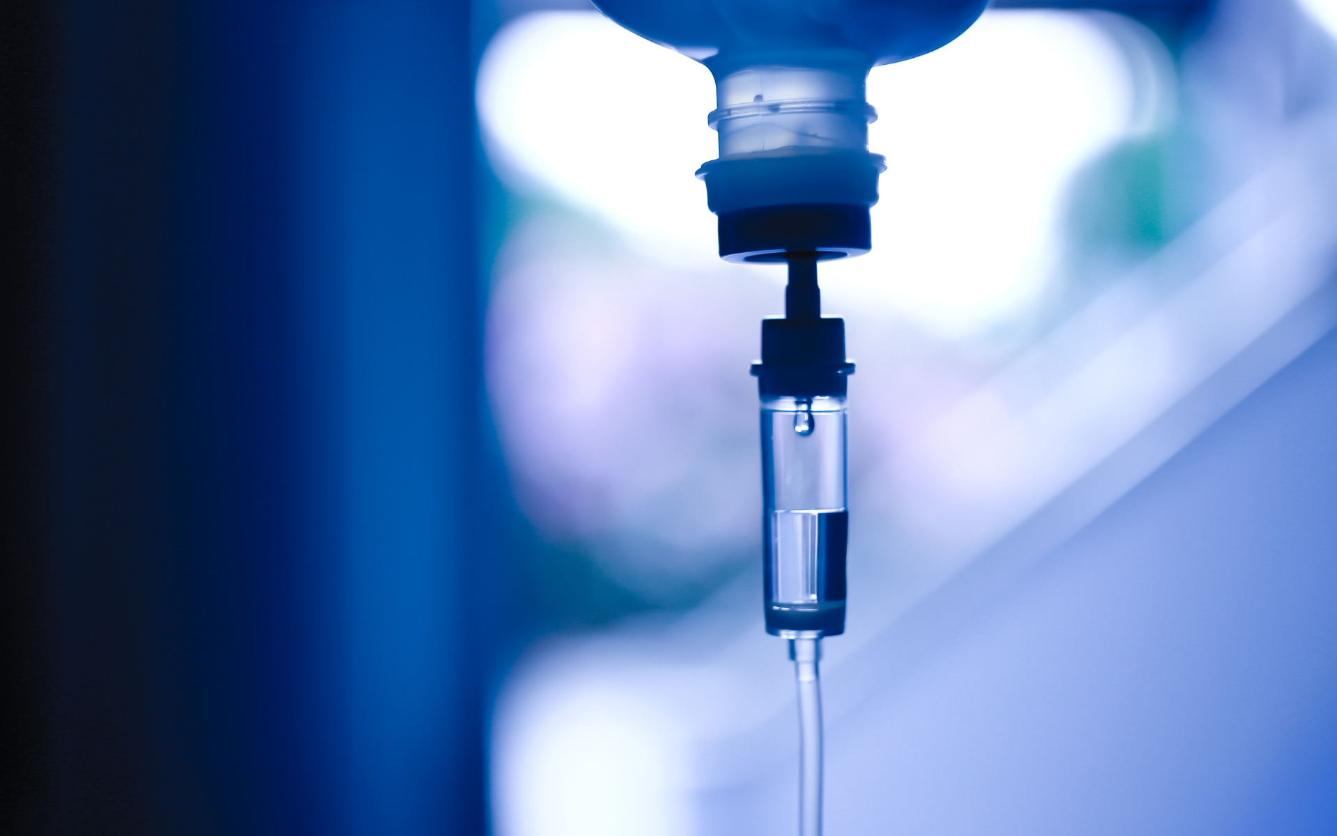 An IV drip in the foreground with an out of focus background.