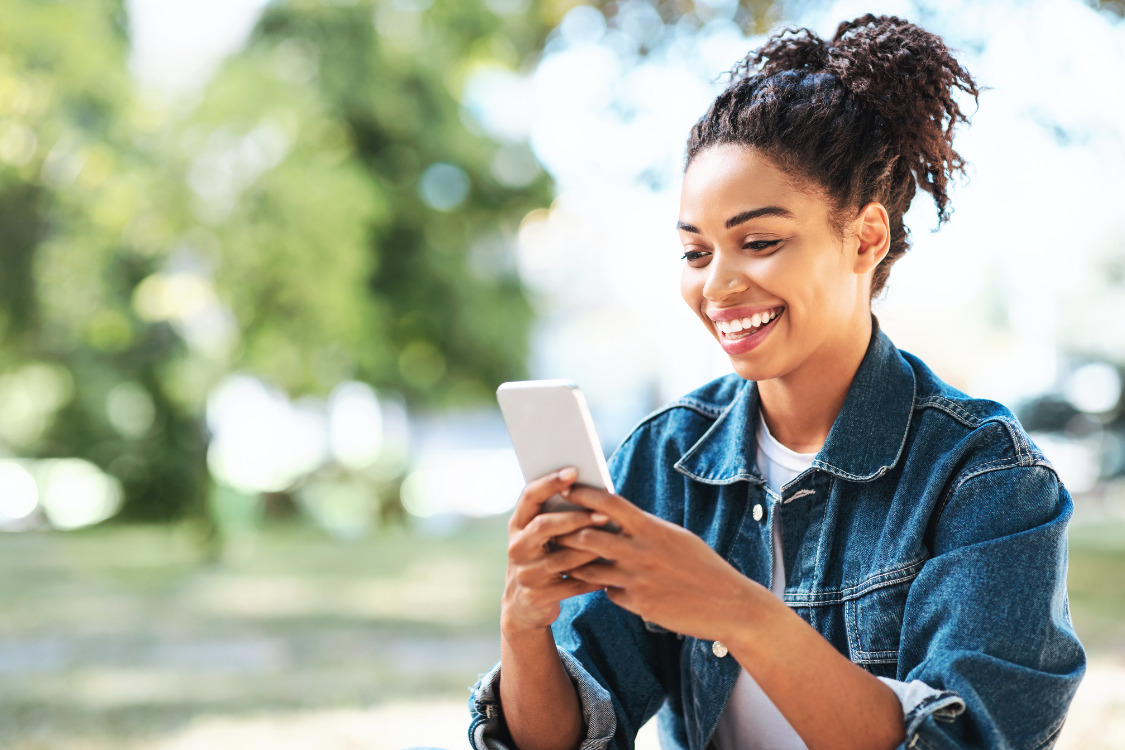 A smiling girl on her phone, outside in Burtonsville, MD.