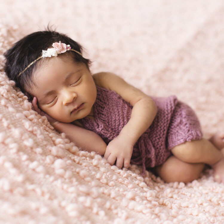 A baby sleeping on a soft pink blanket.