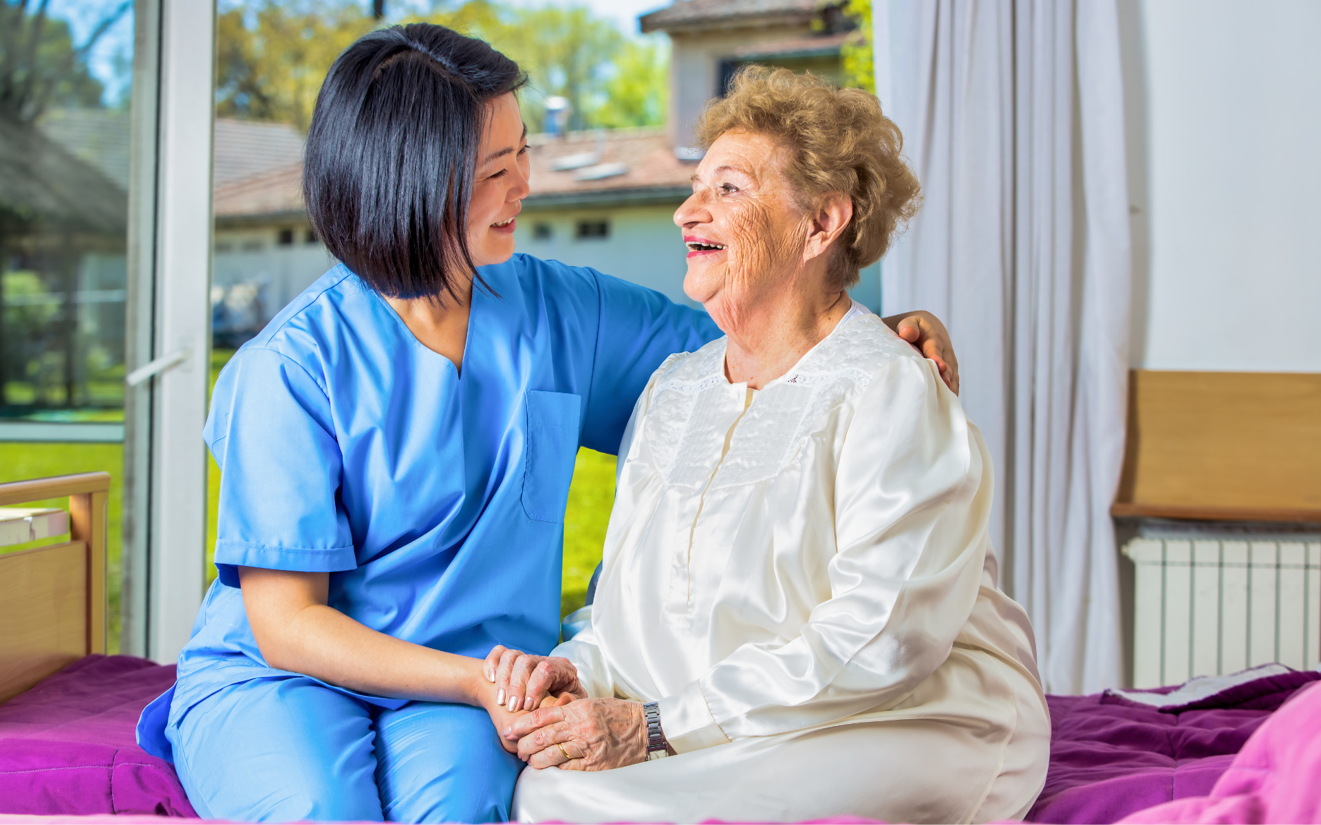 Nurse sitting with patient on bed