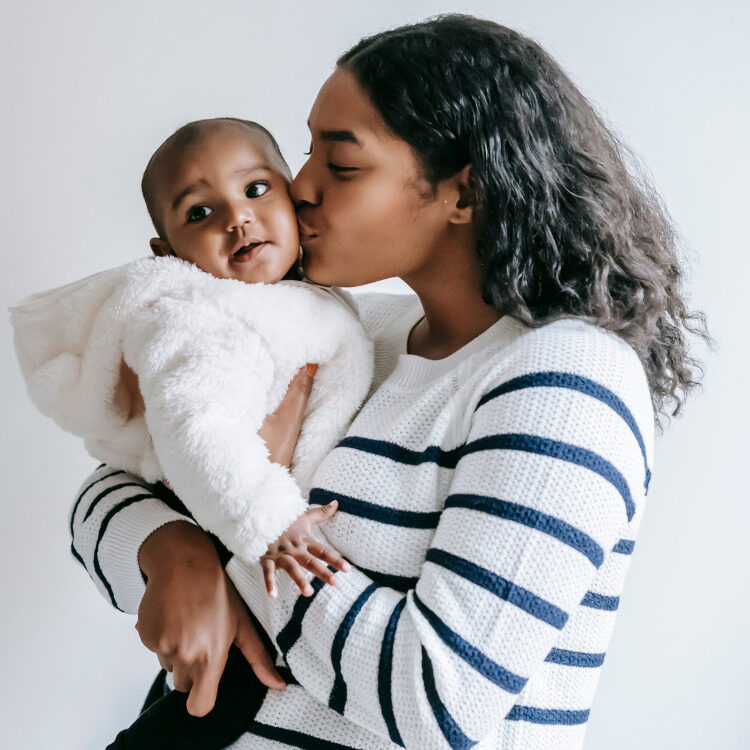 A Burtonsville, MD mother holding and kissing her baby.